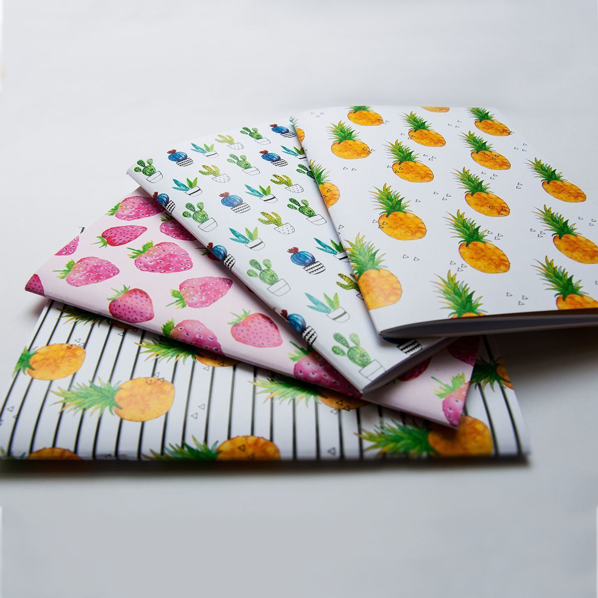 Four notebooks with different patterns on a light gray background