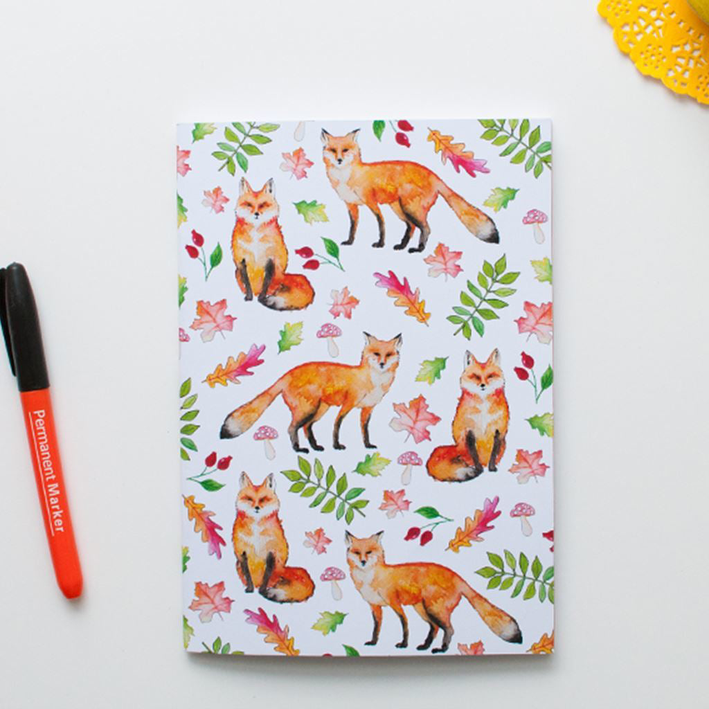 Notebook with fox and leaf pattern on a white background with a marker.