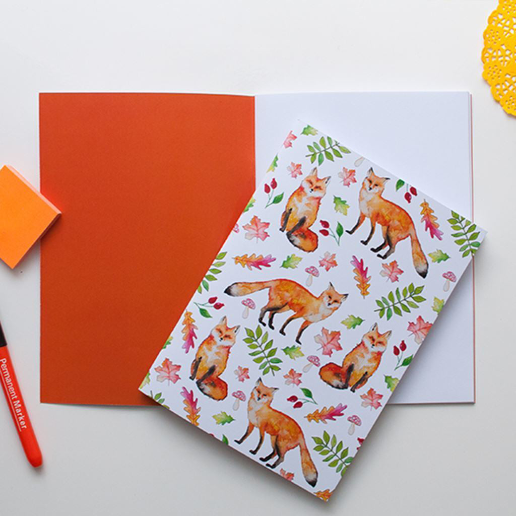 Notebook with fox pattern on cover on top of a notebook with a matching orange inside cover