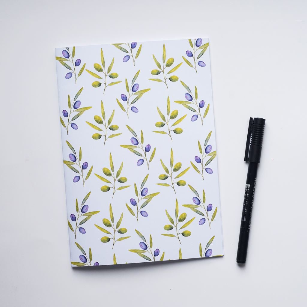Notebook with olive and leaf pattern and pen on a white background