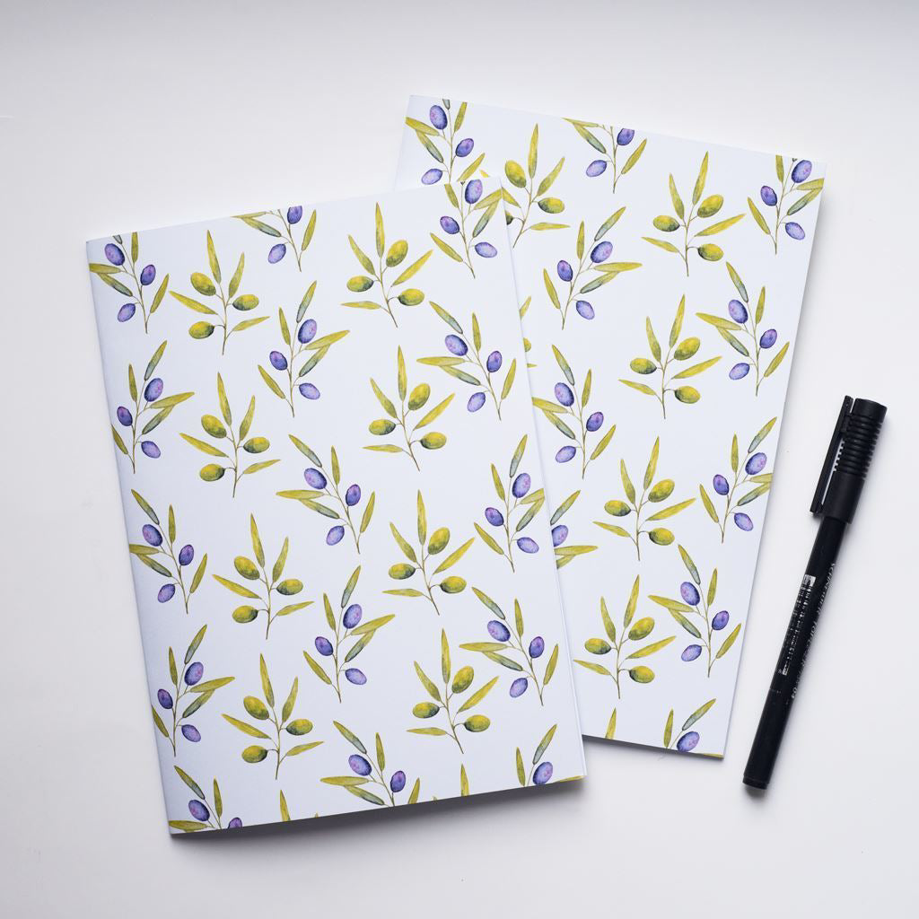 Two notebooks with olive floral pattern and a pen on a white background