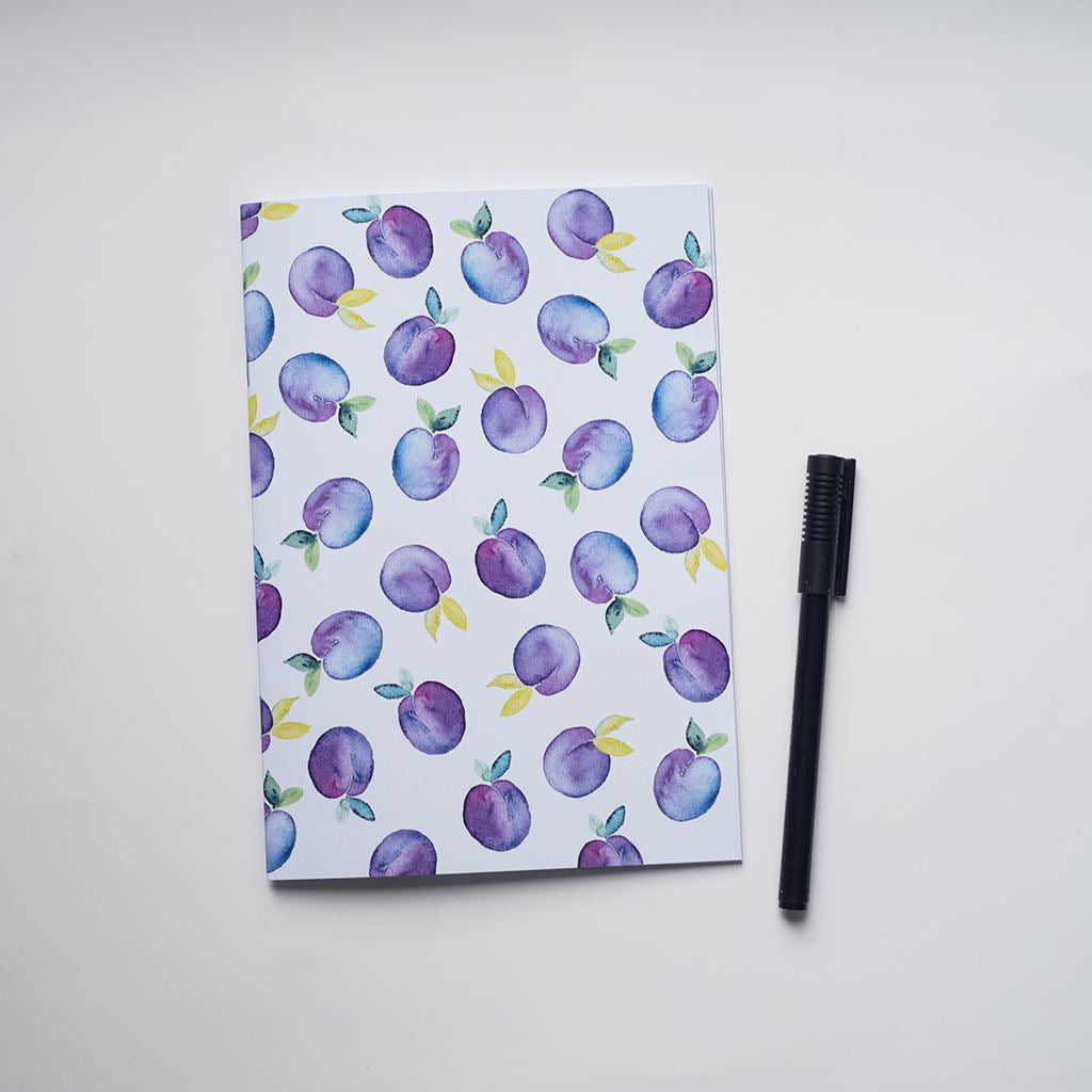 Notebook with plum pattern and a black comb on a white background