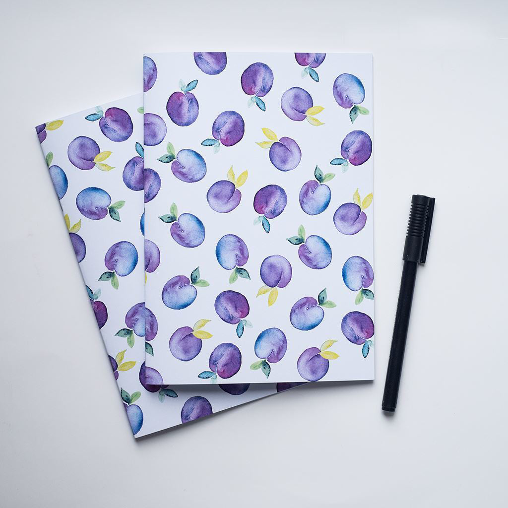 Two notebooks with purple plum pattern on a white background