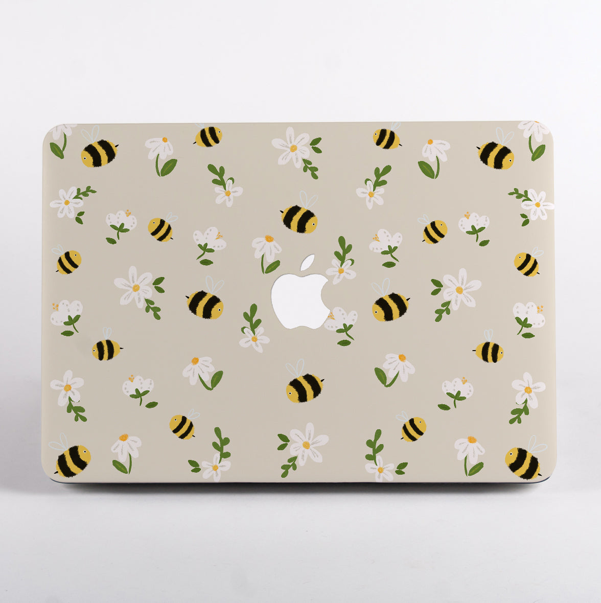 MacBook with a decorative case featuring bees and flowers on a beige background