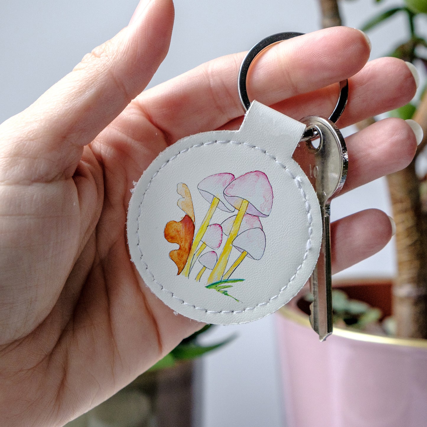 Keychain with mushroom design held by a hand, made from high-quality faux leather and scratch-resistant print.