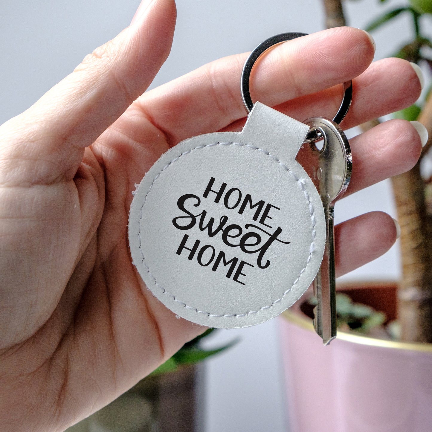 Round leather Keychain with 'Home Sweet Home' text, held by a hand - perfect little gift for new homeowners