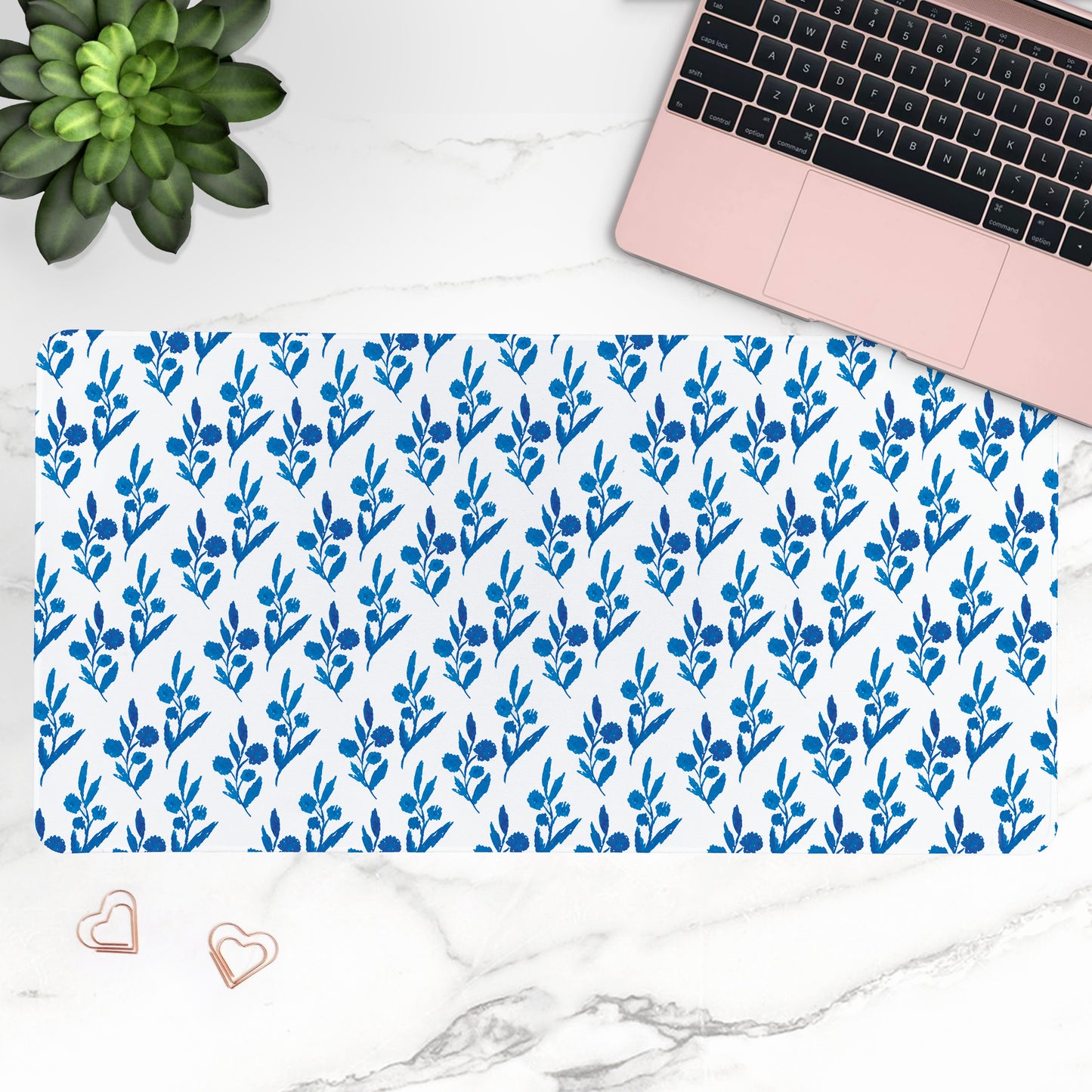 Blue floral patterned desk mat with a laptop and plant on a white marble surface