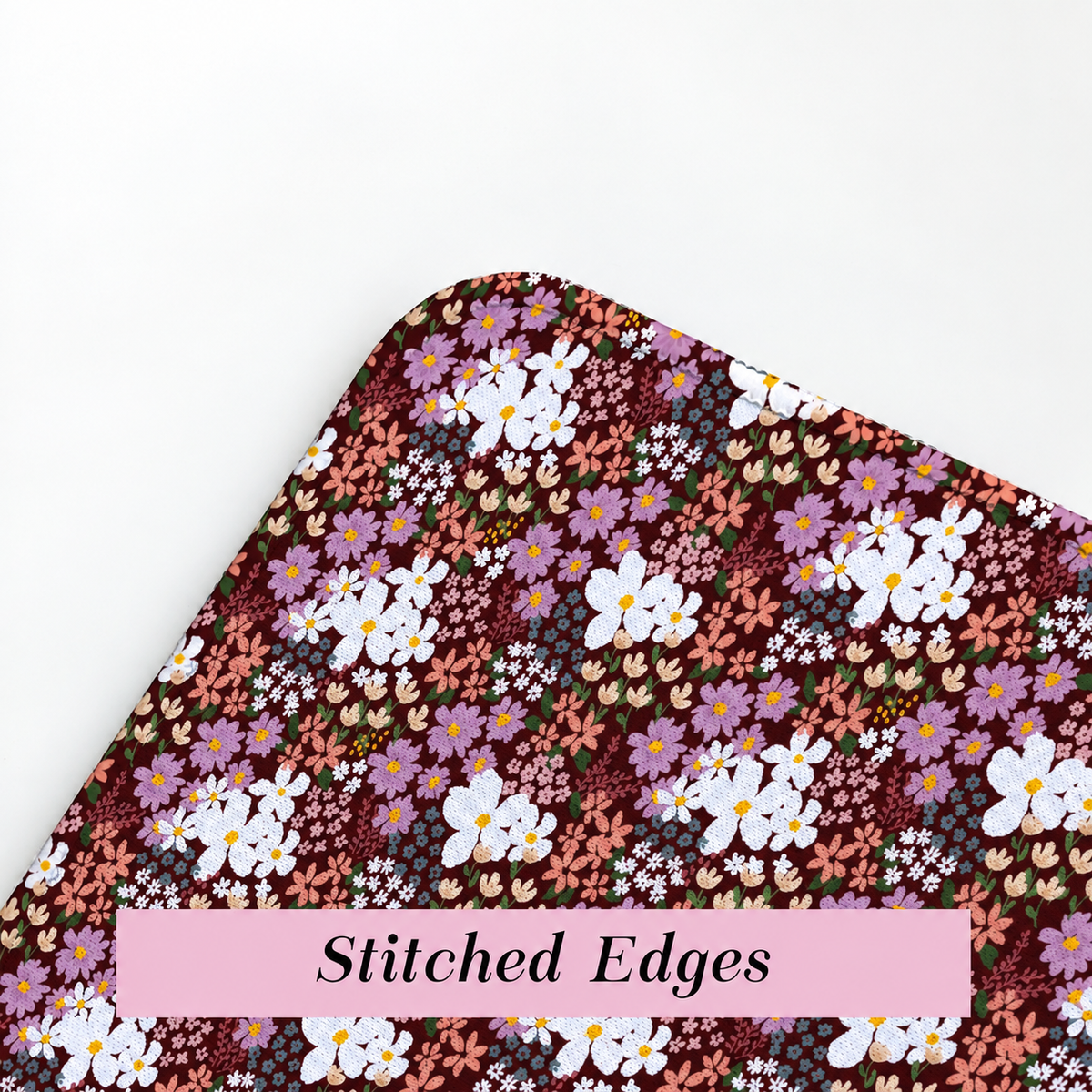 Close-up of burgundy floral desk mat showing the colourful printed fabric surface and durable stitched edges.
