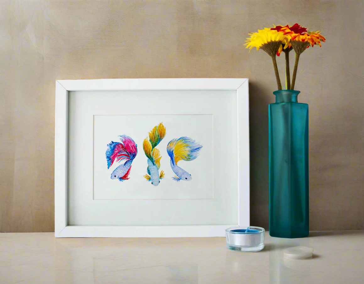 Framed artwork of colorful fish next to a teal vase with flowers on a beige surface.