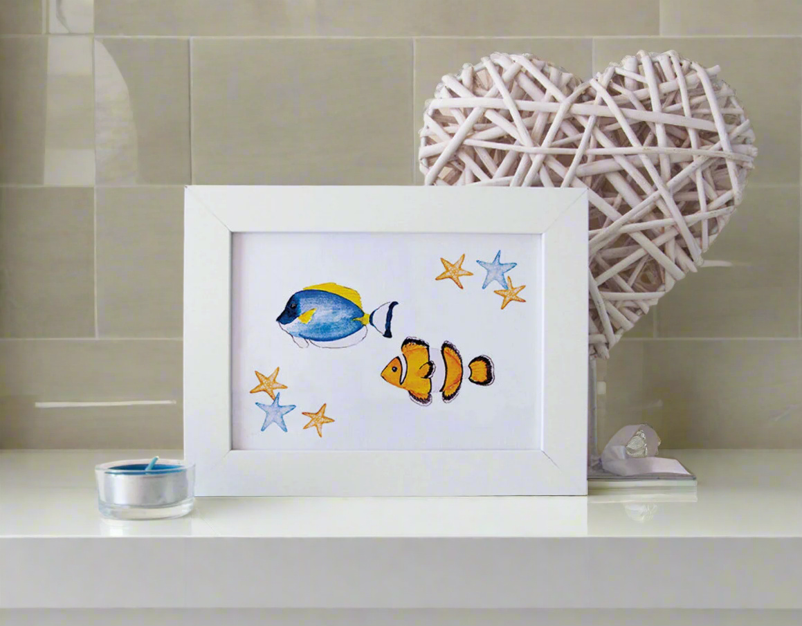 Framed artwork of fish and stars on a shelf with decorative heart and candle.