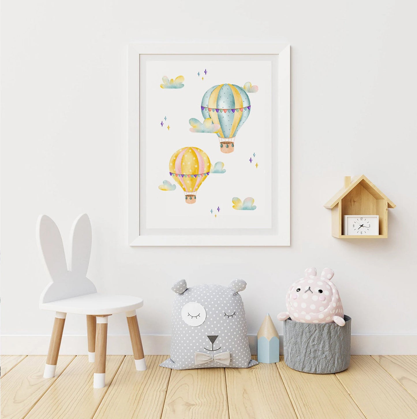 Children's room with a framed artwork of hot air balloons, a chair, and decorative pillows on a wooden floor.