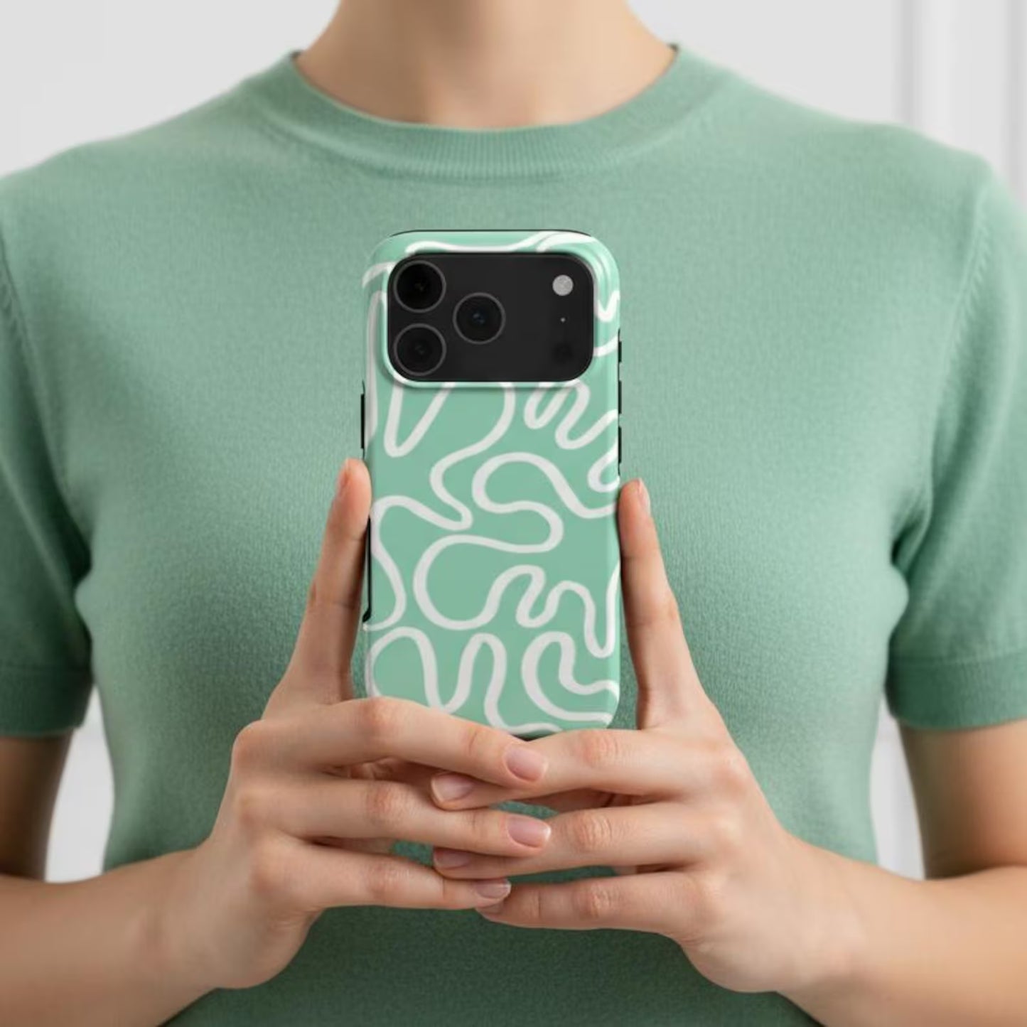 woman holding a minimalsitic tough phone case with white abstract lines on a mint green background — dual-layer protection meets artistic design for those needing extra phone shileding
