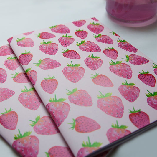 Two notebooks with strawberry pattern on a white surface