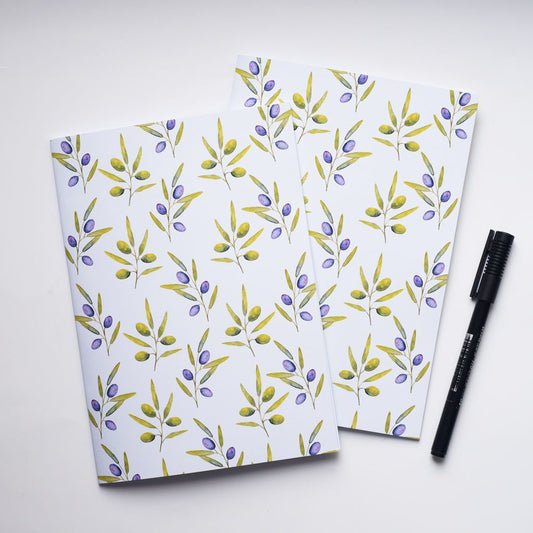 Two notebooks with olive floral pattern and a pen on a white background