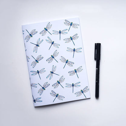 Notebook with dragonfly pattern and a pen on a white background