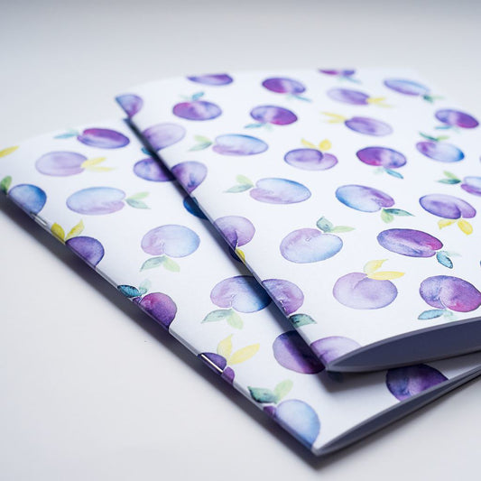 Two notebooks with purple plum pattern on a white background