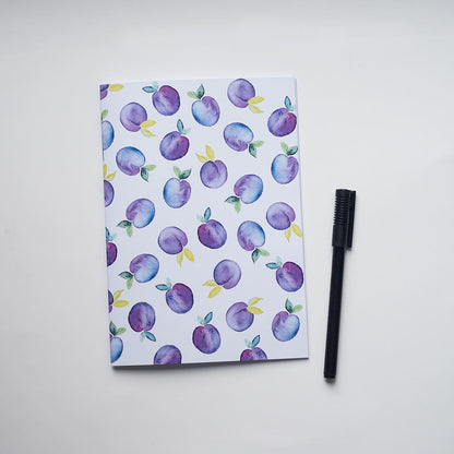 Notebook with plum pattern and a black comb on a white background