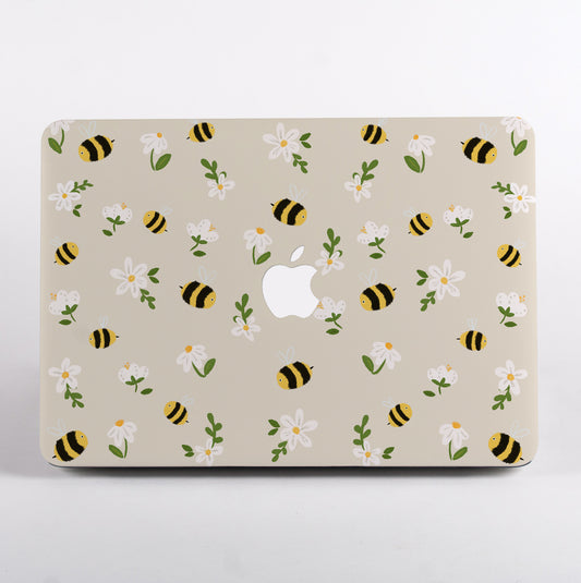 MacBook with a decorative case featuring bees and flowers on a beige background