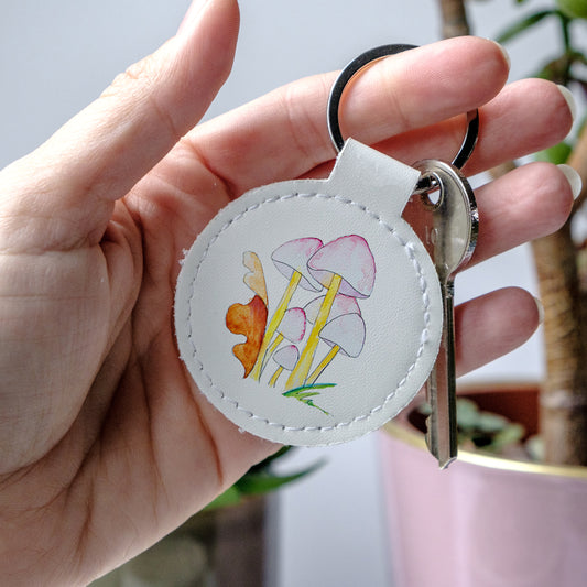 Keychain with mushroom design held by a hand, made from high-quality faux leather and scratch-resistant print.