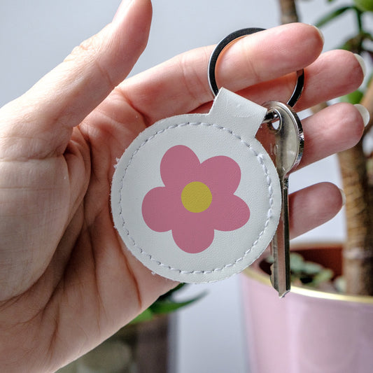 Keychain with a pink flower design held by a hand