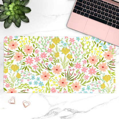 Floral desk mat with laptop, plant, and heart-shaped objects on a marble surface