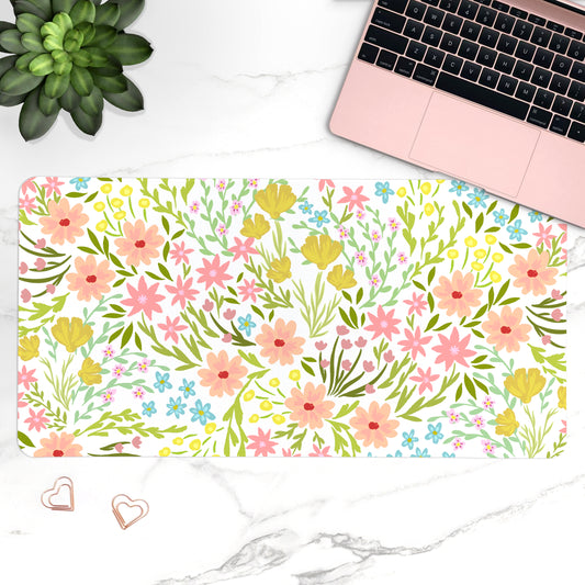 Floral desk mat with laptop, plant, and heart-shaped objects on a marble surface