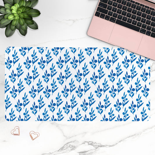 Blue floral patterned desk mat with a laptop and plant on a white marble surface