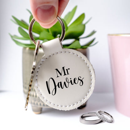 Round white letaher keyring with black writing Mr and customised family name under