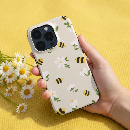 Phone case with bee and flower design held by a hand on a yellow background