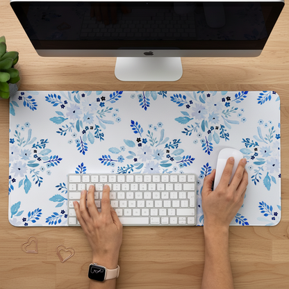 Person using a computer with a blue floral desk mat featuring watercolour flowers on a white background.