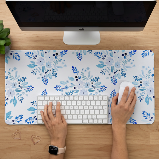 Person using a computer with a blue floral desk mat featuring watercolour flowers on a white background.