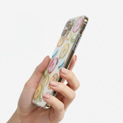 Phone case with donut pattern held by a hand showing transparent sides and responsive buttons