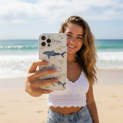 Woman taking a selfie on a beach with a phone case featuring shark designs.