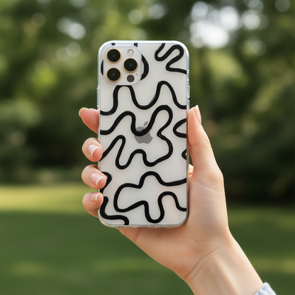 Hand holding a phone with a black artsy wavy lines print against a blurred green outdoor background