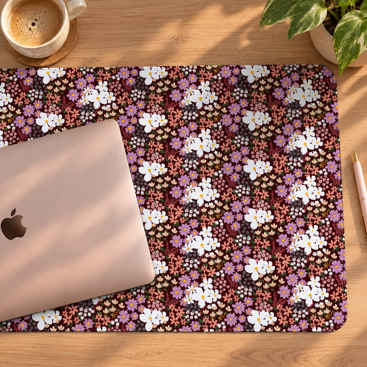Large floral desk mat with burgundy background and colourful flowers, styled with an MacBook in a home office workspace.