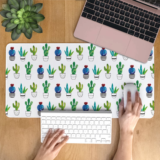 Person using a laptop with a cactus patterned desk mat on a wooden desk.