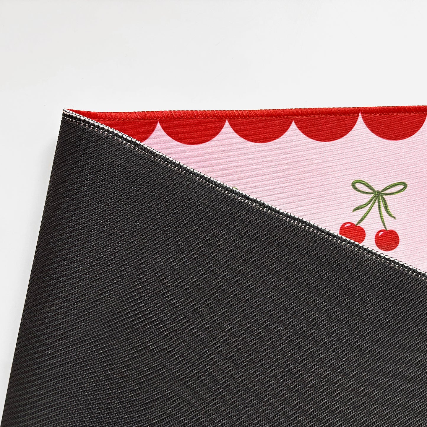 Close-up of the Cute cherry desk matshowing non-slip run=bber base and stitched edges