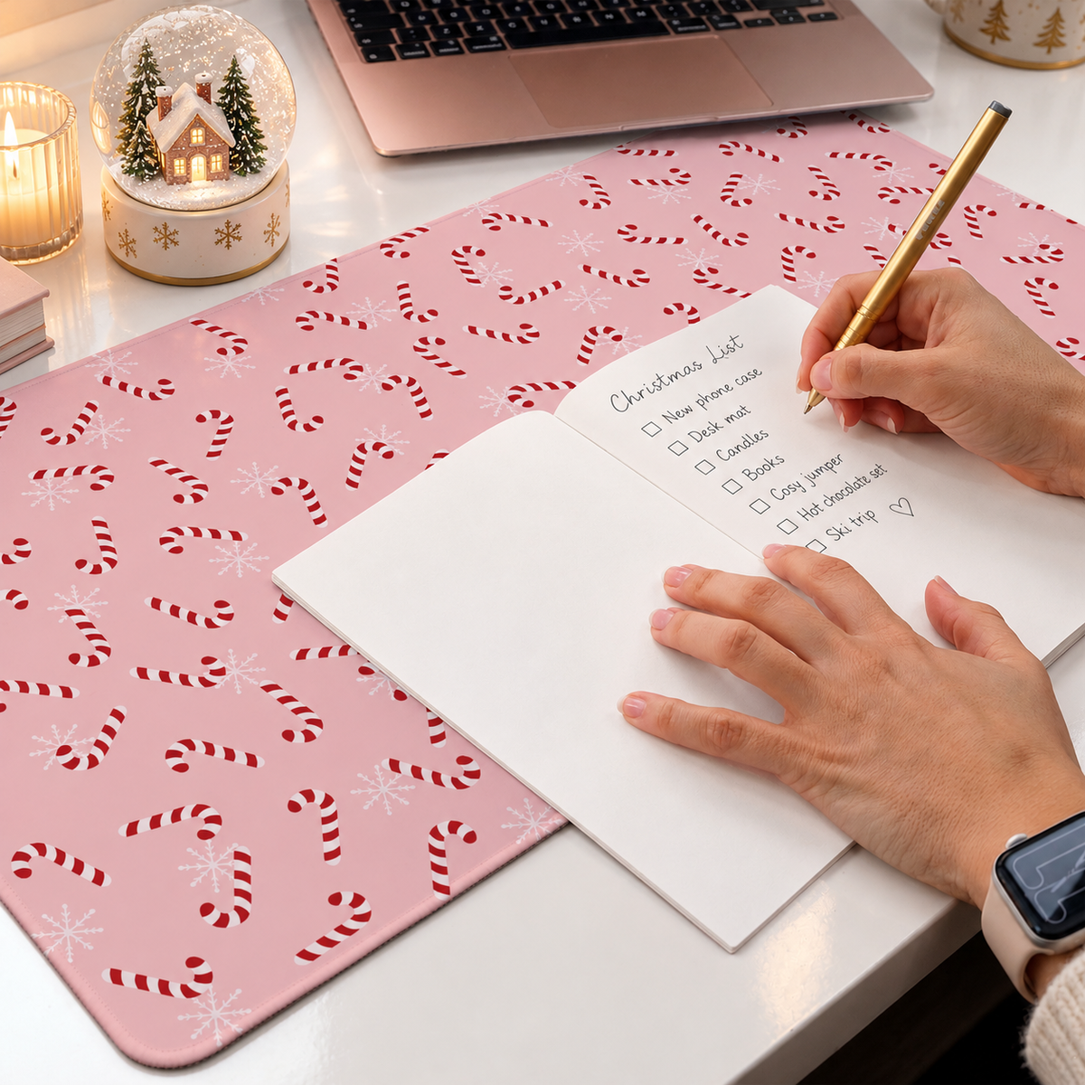 Pink candy cane desk mat styled in a festive workspace with a Christmas snow globe