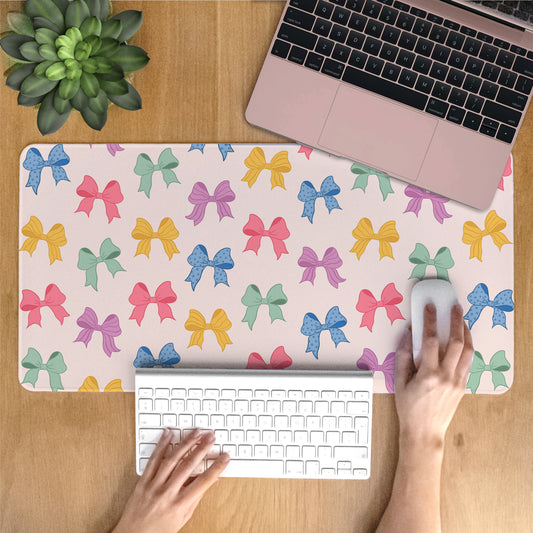 Person using a laptop on a desk with a colorful bow-patterned desk mat.
