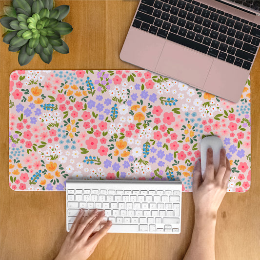 Laptop on a summer floral desk mat with a person using a computer.