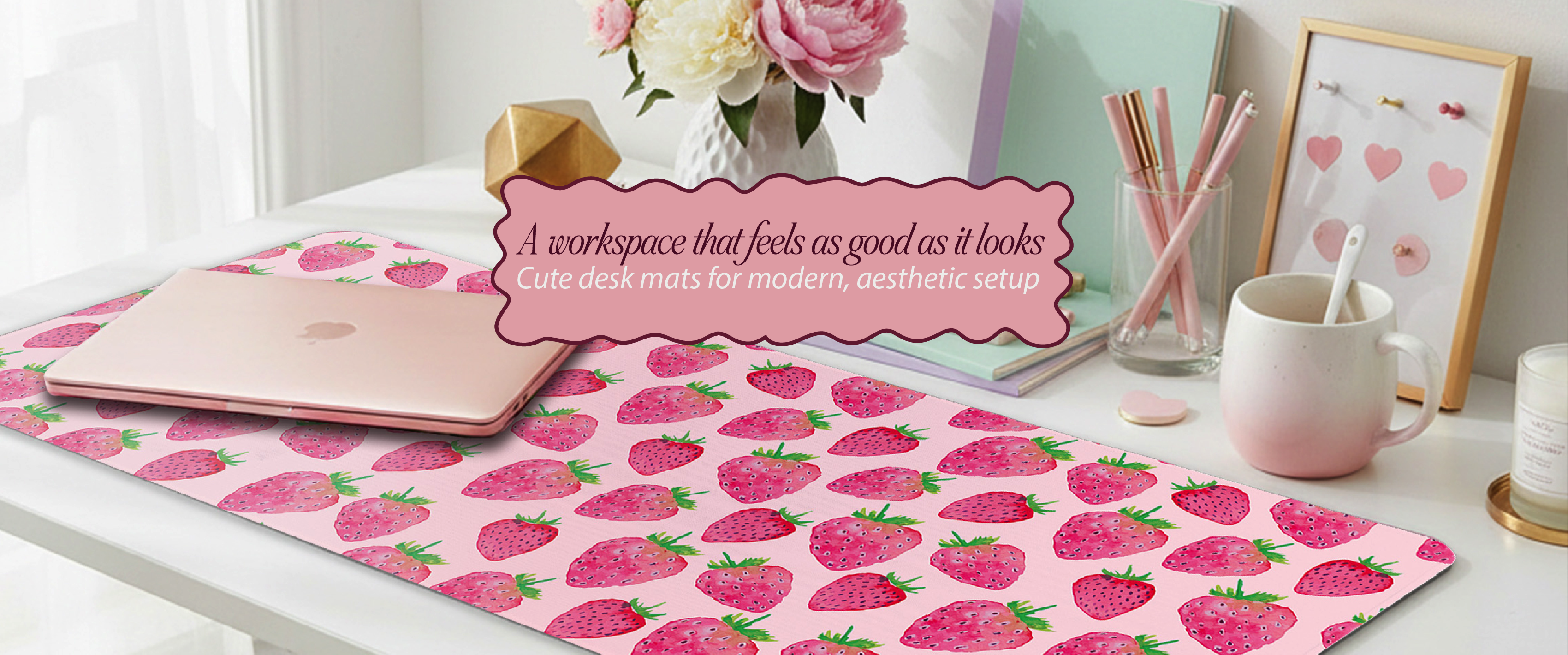 Desk setup with a pink strawberry patterned mat, notebook, mug, and decorative items.