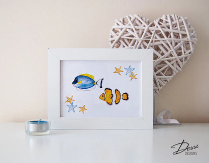 Framed artwork of two fish and stars on a white surface with a decorative heart and candle in the background.