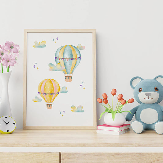 Framed artwork with hot air balloons on a shelf with a teddy bear and flowers.