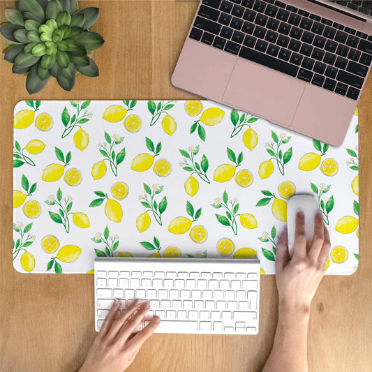 Person using a laptop on a desk with a lemon-patterned desk mat