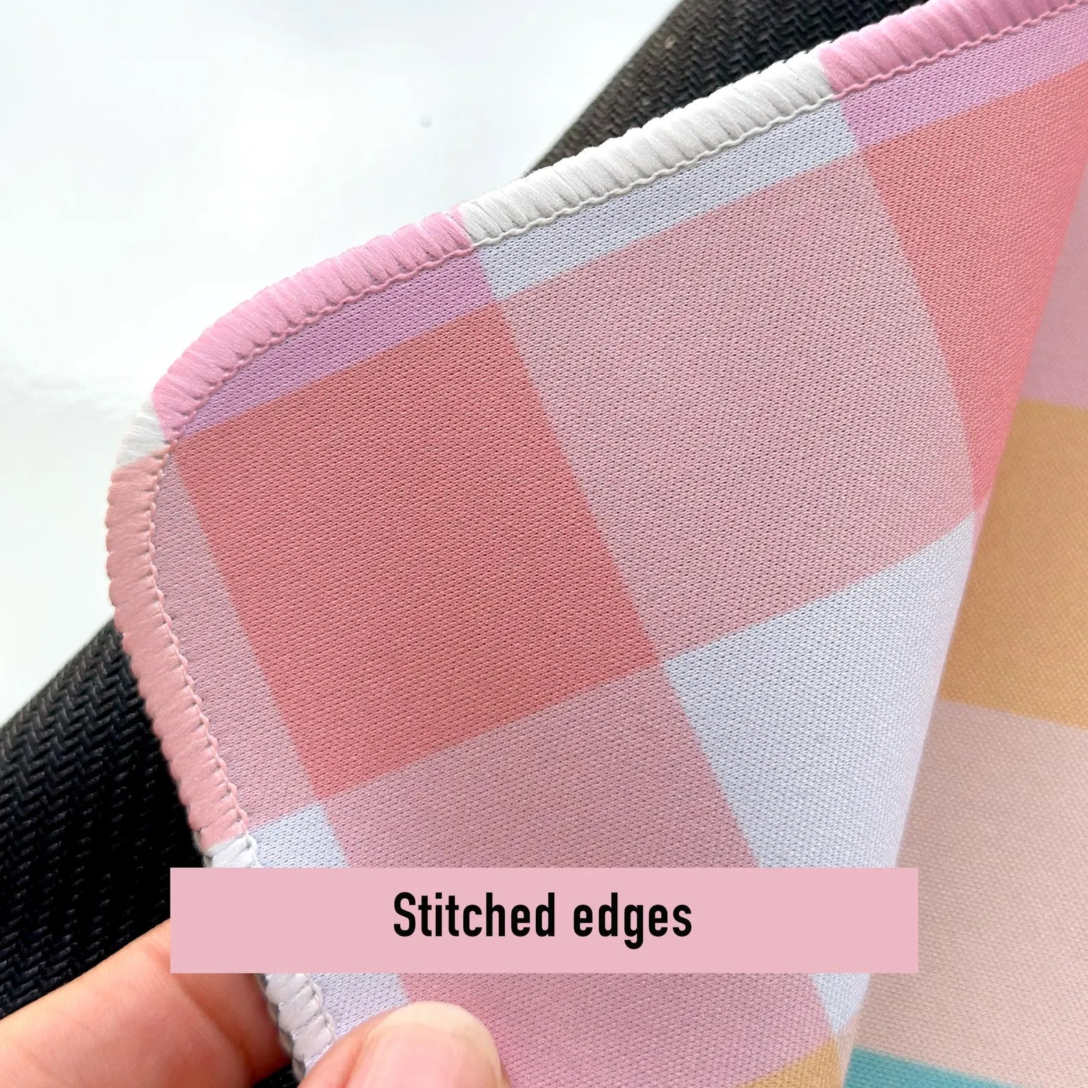 Close up shot of the rainbow plaid desk mat showing stitched edges
