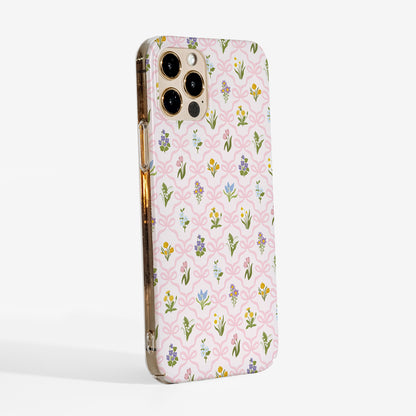 Side view of a floral phone case with a pink bow trellis design and vintage wildflowers printed on a slim hard plastic shell.