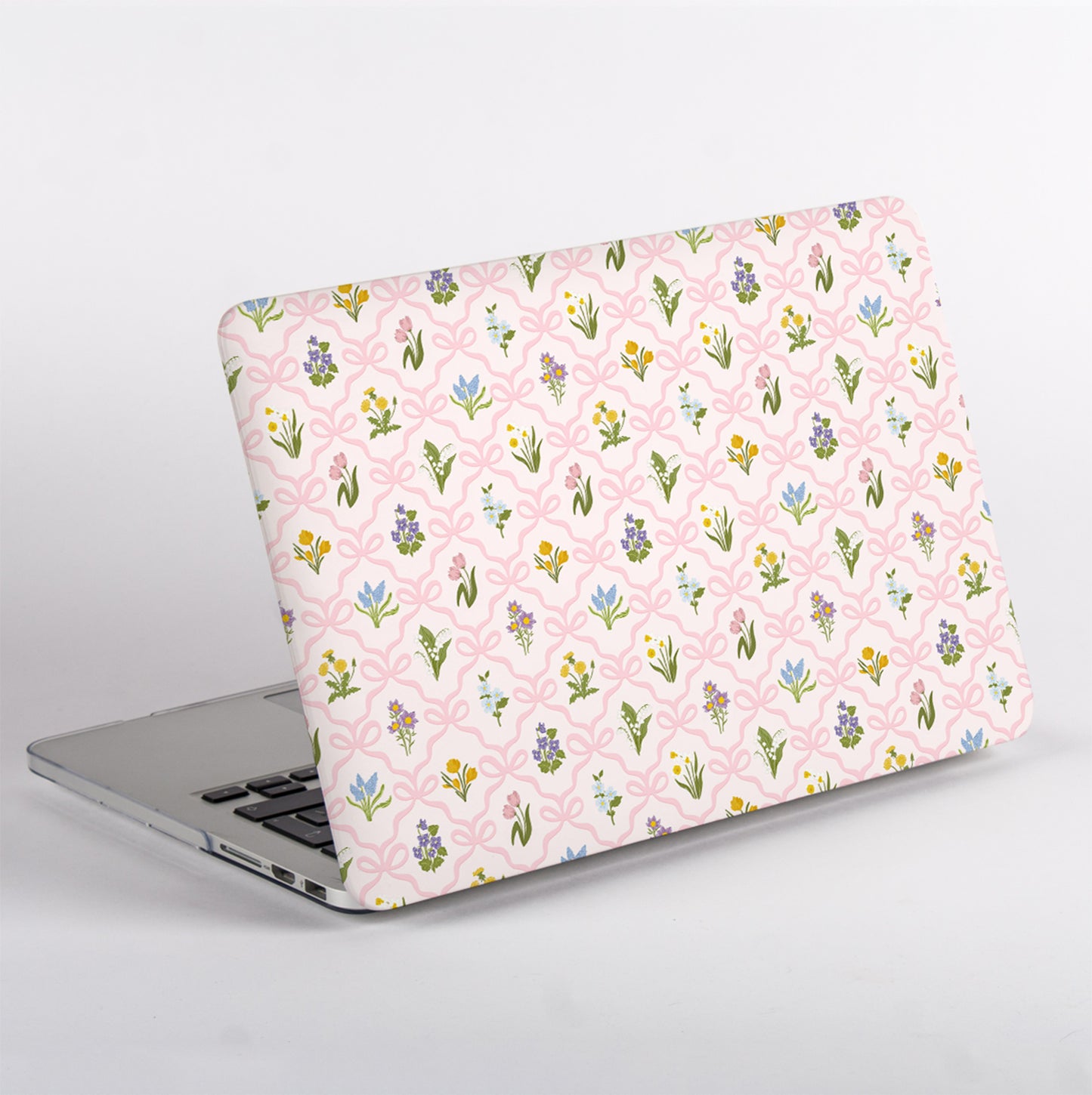 Protective MacBook case designed with vintage-inspired wildflowers and a blush pink bow lattice pattern for a feminine cottage garden aesthetic.